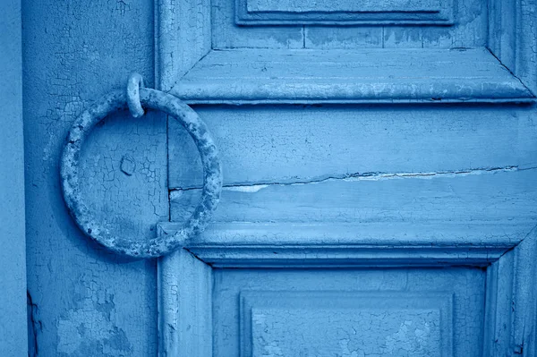 Oude vintage deur met schilferende verf en een roestig handvat in de vorm van een ring. Klassiek blauw. De trend van 2020. — Stockfoto