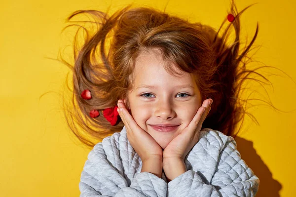 Niña de 6 años sobre un fondo amarillo. Ojos azules y cabello largo. Sonrisas. La ternura y una infancia feliz . — Foto de Stock