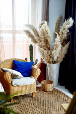 Bir sandalye ve rattan yapılmış bir halı. Doğal malzeme. Vazoda pampas otu. Eko tasarımı..