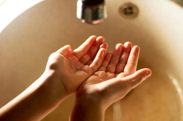Ребенок моет руки, защищает от бактерий. Вечернее освещение, теплый свет . — стоковое фото