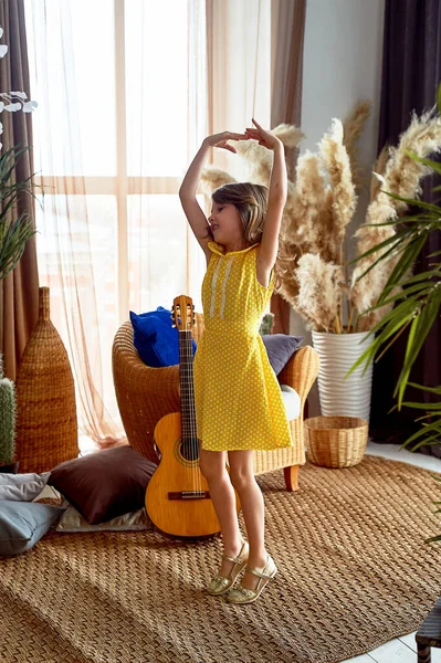 A happy 6-year-old girl in a yellow dress whirls and dances at home.Dream of becoming a Princess or a ballerina.