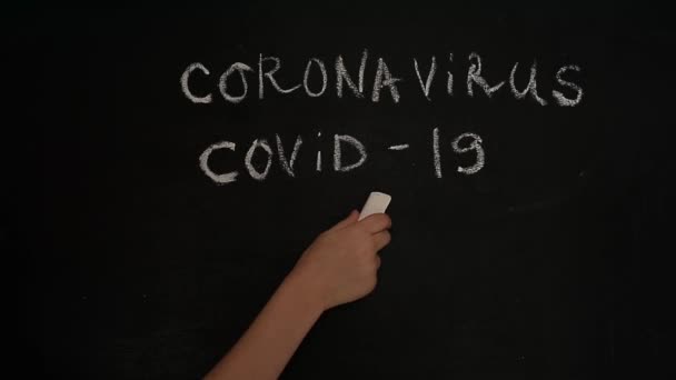 Coronavírus. Covid-19.A mão das crianças desenha um rosto sorridente triste em um quadro negro com giz. Quarentena, ensino à distância — Vídeo de Stock