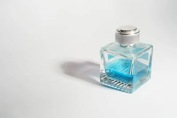 Parfüm in einer transparenten Flasche, hellblau auf weißem Hintergrund. Aromatherapie, Parfümerie. Raum für Text. — Stockfoto