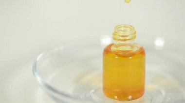 Hafif bir arka planda hafif cam bir şişede aromatik yağ. Düşüyor. Ruh yaratıyor. Spa tedavileri.
