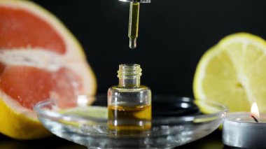 Hafif bir arka planda hafif cam bir şişede aromatik yağ. Düşüyor. Ruh yaratıyor. Spa tedavileri. Limon ve greyfurt.