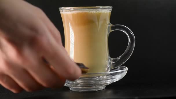 Té con leche o café en una taza transparente. Ponen galletas en un platillo. Fiesta del té. El fondo es negro . — Vídeos de Stock