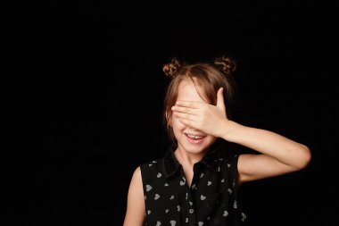 Siyah arka planda 6 yaşında bir kız. Bir sürpriz, bir hediye umuduyla gözlerimi kapadım. Yüzünde bir gülümseme vardı..