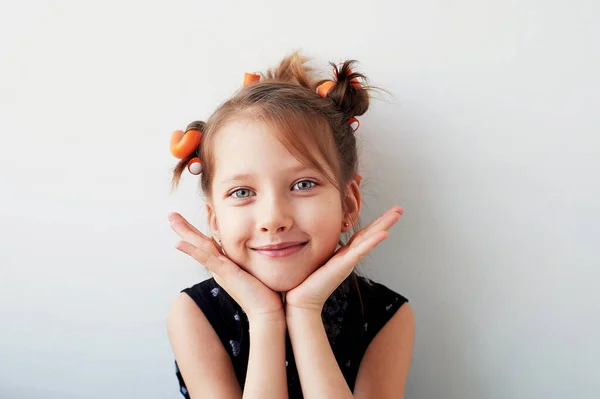 Una niña de 6 años con rulos en la cabeza. La búsqueda de la belleza.Niños joys.Isolated sobre un fondo blanco . — Foto de Stock
