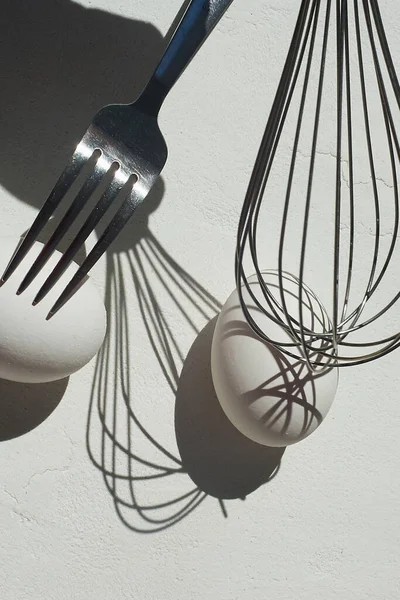 Egg with shadow from the fork. Minimalism. Cooking pastries, omelets. Easy. Whisk for whipping.