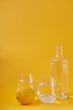 Sarı arka planda limonlu ferahlatıcı su. Sağlıklı yaşam tarzı, susuzluk giderme.