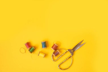 Sarı arka planda iplikleri olan renkli bobinler. El sanatları ve dikiş..