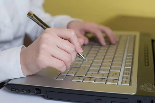 Las manos de la mujer escribiendo en el teclado portátil. Sujetando la pluma en el brazo. Enfoque selectivo a mano. Se puede utilizar para la tecnología, el negocio y el concepto de Internet . — Foto de Stock