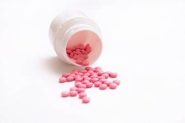 Beyaz arka plan üzerinde izole şişe pembe hap dışarı dökülme.