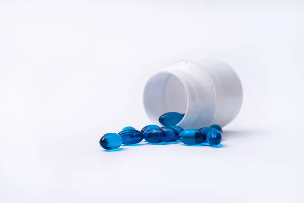Las píldoras azules se derraman de la botella aislada sobre fondo blanco . — Foto de Stock