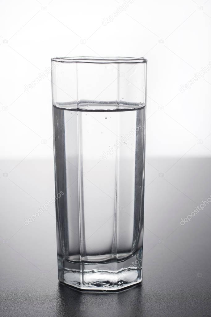 Glass of water on table with reflection.