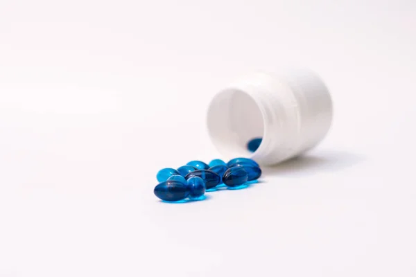 Blauwe pillen morsen uit fles geïsoleerd op witte achtergrond. Stockfoto