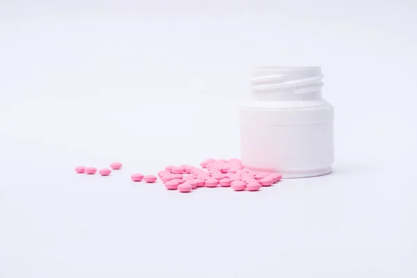 在白色背景查出的粉红药丸和药瓶. 免版税图库照片