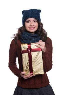 Noel hediyesi tutan örme kazak, atkı ve şapka, oldukça neşeli seksi genç kadın. Beyaz arka plan üzerinde izole. O gülümseyen ve duygular gösterilen. Kış giysileri.