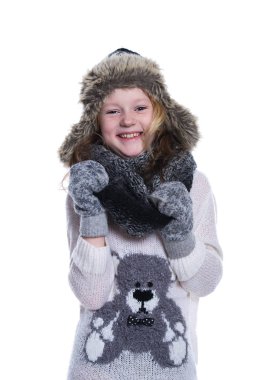 Stüdyoda poz mutlu güzel bir çocuk. Kış giysileri giyiyor. Örgü yün kazak ve eldivenler. Kulak kapakları kürk kap. Beyaz arka plan üzerinde izole.