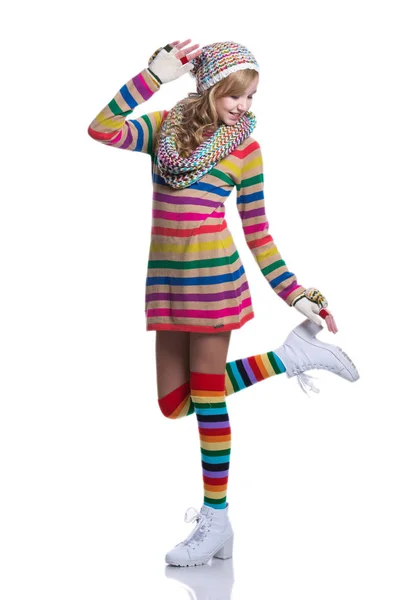 Χαριτωμένο χαρούμενα εφηβικό κορίτσι που φοράει πολύχρωμα ριγέ πουλόβερ, κασκόλ, γάντια, καπέλο και λευκές μπότες απομονωμένη. Χειμωνιάτικα Ρούχα. — Φωτογραφία Αρχείου
