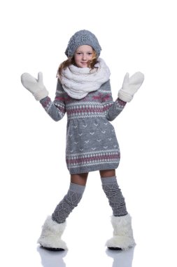 Beyaz arka plan üzerinde izole Studio poz mutlu güzel bir çocuk. Kış giysileri giyiyor. Örgü yün kazak, atkı, şapka, eldiven ve moda kışlık botlar ile kürk.