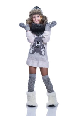 Stüdyoda poz mutlu güzel bir çocuk. Kış giysileri giyiyor. Örgü yün kazak ve eldivenler. Kulak flep kap kürk ve kürk botları Kış moda... Beyaz arka plan üzerinde izole.