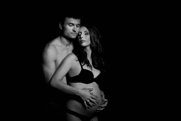 Retrato monocromático de casal amoroso feliz em um momento de amor e ternura. Mulher grávida com as mãos sobre a barriga. Foto em preto e branco . — Fotografia de Stock
