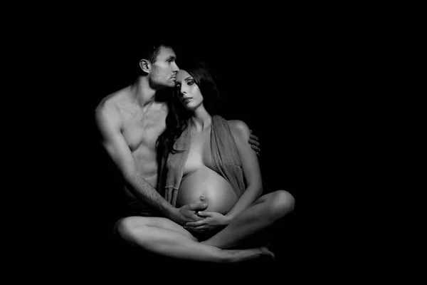 Retrato monocromático de casal amoroso feliz em um momento de amor e ternura. Mulher grávida com as mãos sobre a barriga. Foto em preto e branco . — Fotografia de Stock