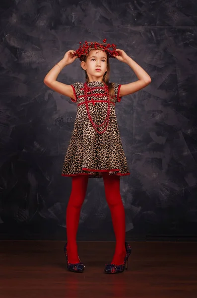 Csinos lány szép ruhát visel. Ő visel piros gyöngyök és koszorú. Stúdió felvétel. — Stock Fotó
