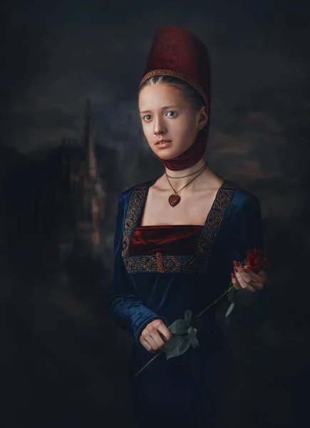 Retrato de una hermosa chica en vestido medieval y tocado. Medallón en forma de corazón. Sujetando rosa roja en las manos . — Foto de Stock