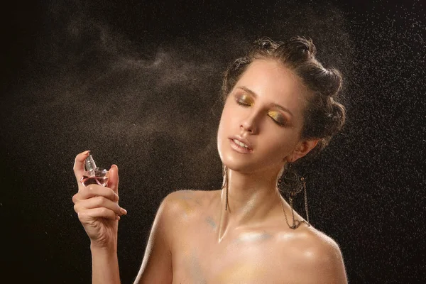 Parlak makyaj ile güzel kadınların duygusal moda portre. Parfüm şişesi tutarak. Hareket su püskürtme. Islak cilt ve yüz. Stüdyo bir siyah arka plan üzerine ateş.