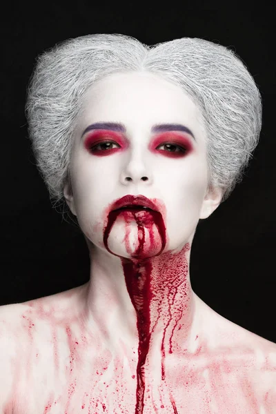 Mysterious beauty portrait of snow queen covered with blood. Bright luxury makeup. Gore dripping from the mouth.