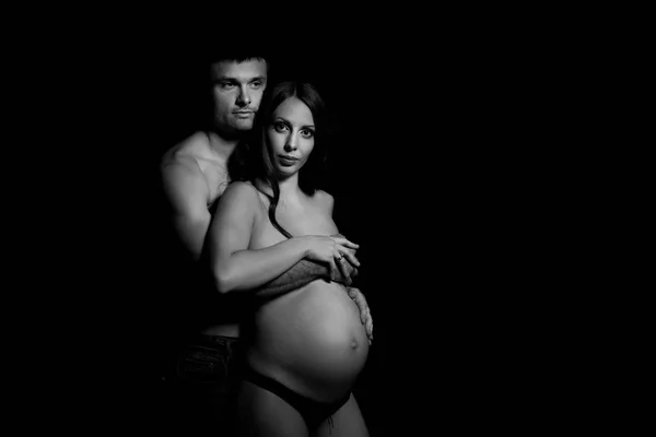 Retrato monocromático de feliz pareja amorosa en un momento de amor y ternura. Mujer embarazada con las manos sobre la barriga. Foto en blanco y negro . —  Fotos de Stock