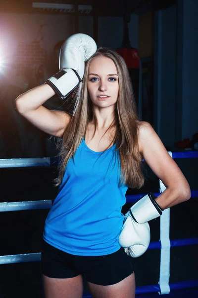 Aantrekkelijke jonge vrouw met witte bokshandschoenen poseren in de boksring. — Stockfoto