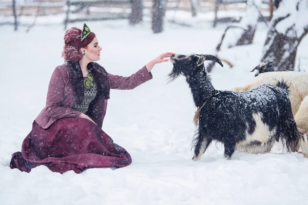 Porträt einer hinreißenden jungen Frau in einem Kleid im russischen Stil bei starkem Frost an einem verschneiten Wintertag im Dorf. russisches Model Mädchen in traditioneller Kopfbedeckung. — Stockfoto