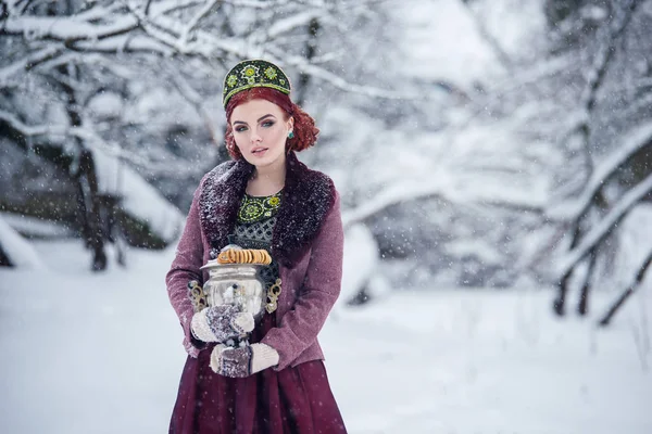 Russian folk style redhead girl holding samovar in a fur coat in snowy winter. — Stock Photo, Image