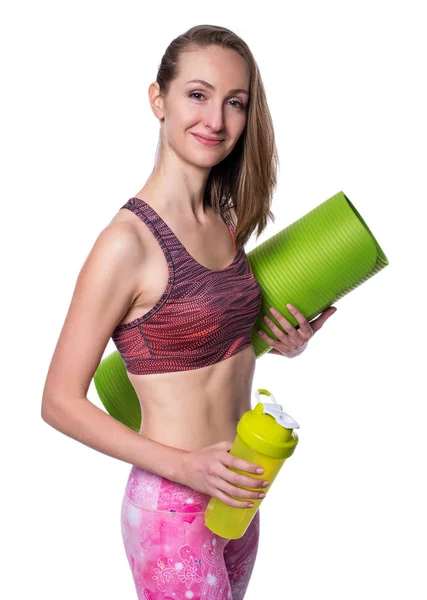 Felice donna sportiva con stuoia verde e shaker guardando la fotocamera in studio. Isolato su sfondo bianco . — Foto Stock