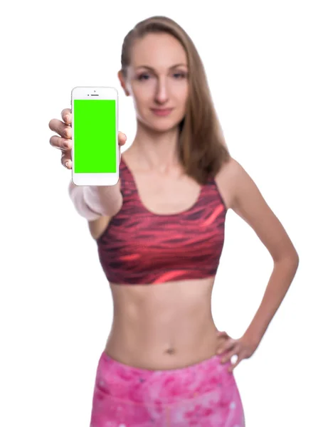 Mutlu gülümseyen fitness kız gösteren chromakey smartphone ekran Studio. Beyaz arka plan üzerinde izole. — Stok fotoğraf