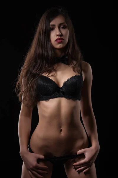 Csábító fiatal nő pózol fekete szexi fehérnemű. — Stock Fotó