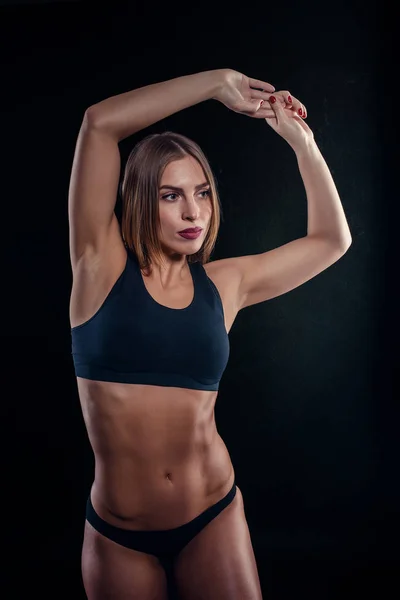 Chica deportiva con grandes músculos en ropa deportiva negra. Mujer atlética joven bronceada. Un gran deporte cuerpo femenino. Muscular construir hembra después del entrenamiento . — Foto de Stock