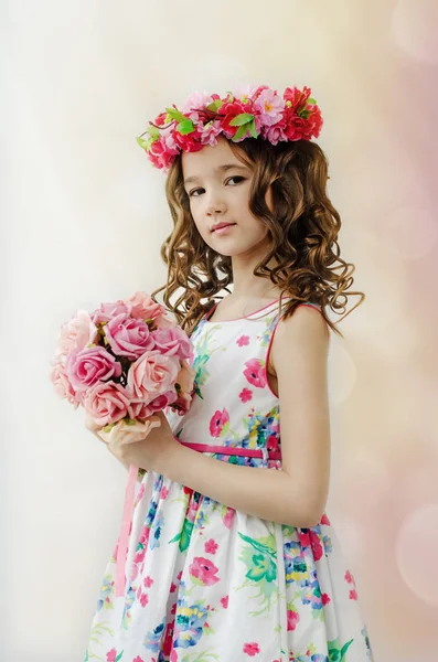 Aranyos kislány, a szép tavaszi ruhát, fején, virágos koszorúzta portréja tart csokor virág. — Stock Fotó