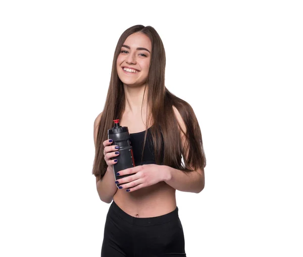 Retrato de sorridente jovem desportista com uma garrafa de água posando em estúdio isolado sobre fundo branco . — Fotografia de Stock