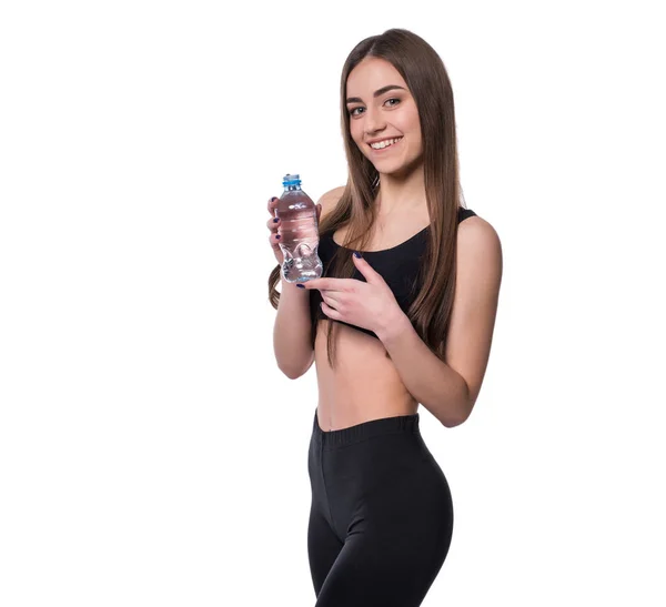 Modelo de fitness feminino positivo após o treino segurando uma garrafa de água pura sobre fundo branco . — Fotografia de Stock