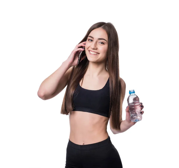 Ritratto di una giovane atleta che ascolta musica con auricolari su sfondo bianco. Attraente fitness ragazza in chat su smartphone ion studio . — Foto Stock