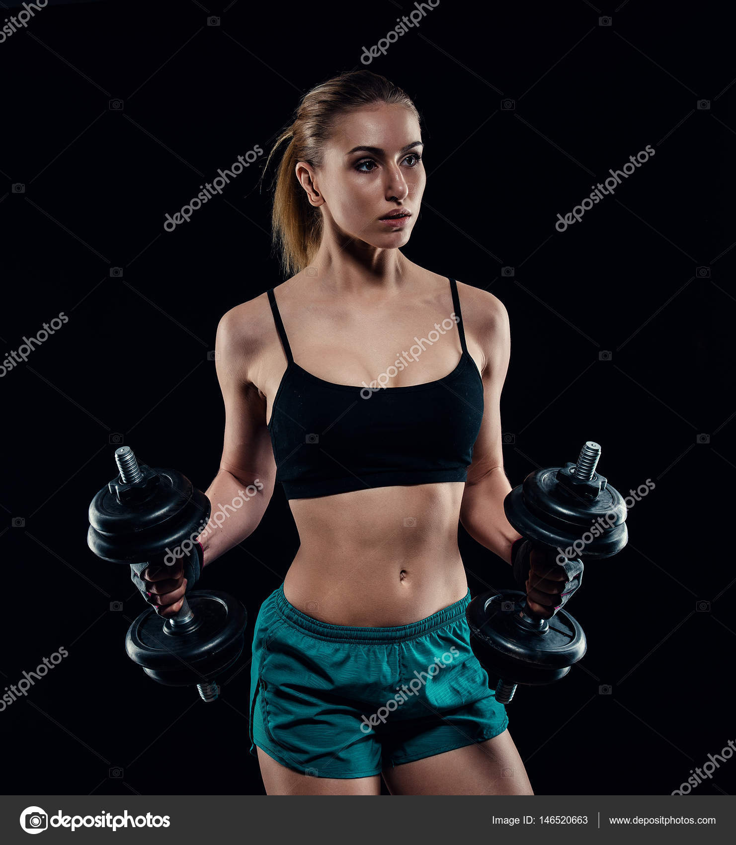 Cute athletic model girl in sportswear with dumbbells in studio