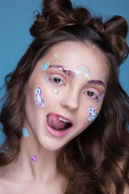 Yüzünde yapıştırılmış komik profesyonel makyaj ve emoji çıkartma ile kız güzel moda.