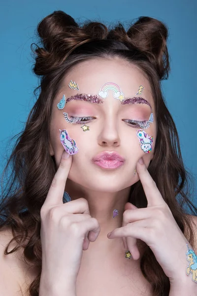 Yüzünde yapıştırılmış komik profesyonel makyaj ve emoji çıkartma ile kız güzel moda.