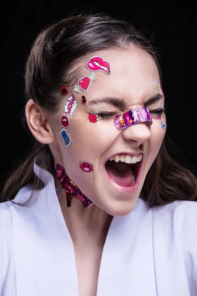 Moda Piękny Dziewczyna z luksusowych profesjonalny makijaż i emoji śmieszne naklejki przyklejone na twarzy. — Zdjęcie stockowe