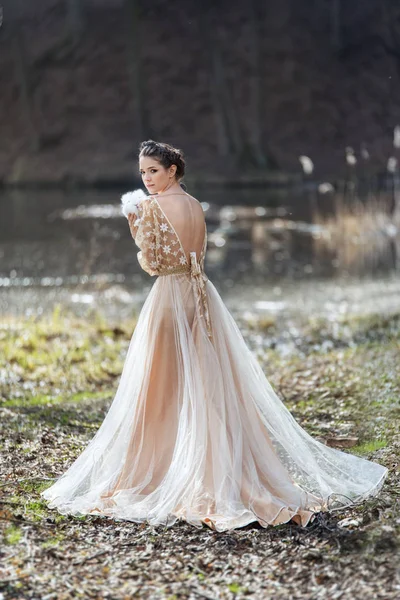Portret van vrouw dragen elegante jurk staande in de buurt van het meer met konijn in handen. — Stockfoto