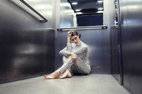 Unga cyber kvinna i silver futuristisk kostym som sitter i hissen. — Stockfoto